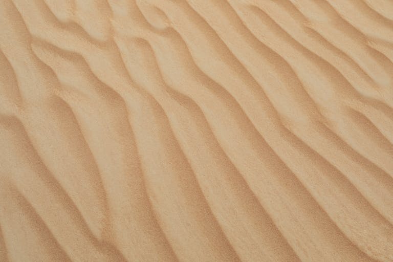 A serene view of golden sand dunes with smooth textures in Dubai's desert, perfect for backgrounds and wallpapers.