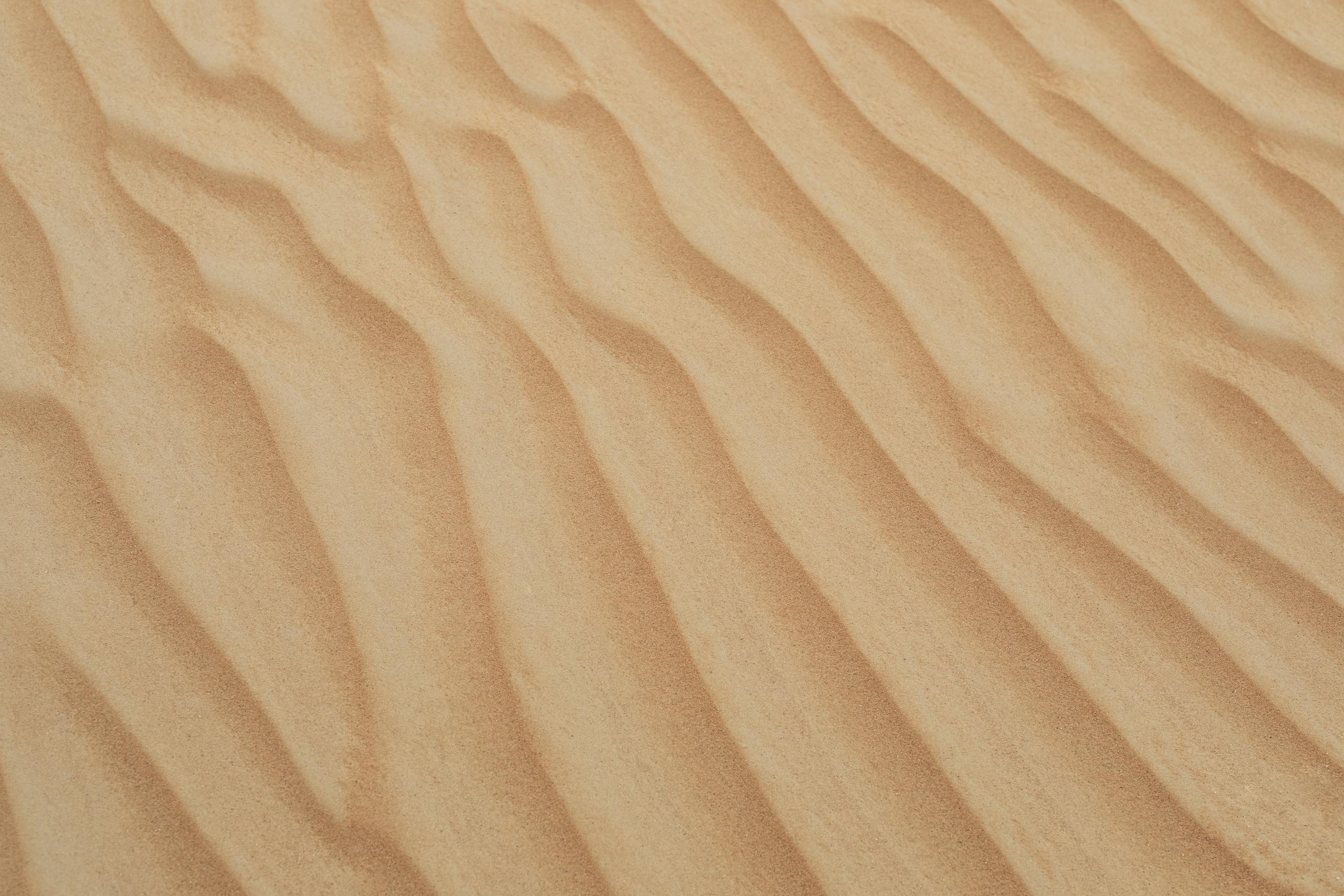 A serene view of golden sand dunes with smooth textures in Dubai's desert, perfect for backgrounds and wallpapers.